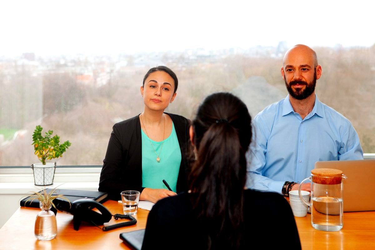# Image Description
This image depicts a professional job interview or meeting scenario, with two interviewers seated…